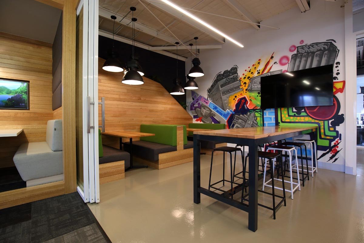 Hocking Stuart high table next to a TV and some booth seating. The wall features a bright mural