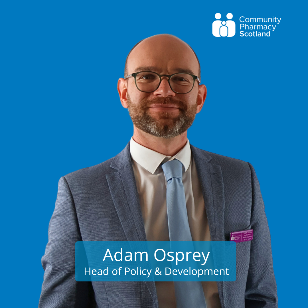 A professional man in a suit with glasses and a beard, standing against a blue background with the Community Pharmacy Scotland logo, and a caption reading 'Adam Osprey, Head of Policy & Development.'