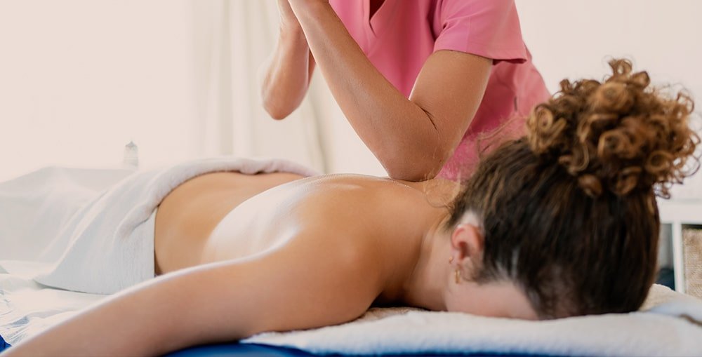 Therapist applying firm pressure along client’s back, demonstrating advanced massage techniques used for deep tension release.