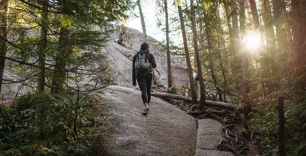 Hiker walking a forest trail on Vancouver’s North Shore, representing endurance strain and the need for recovery care.