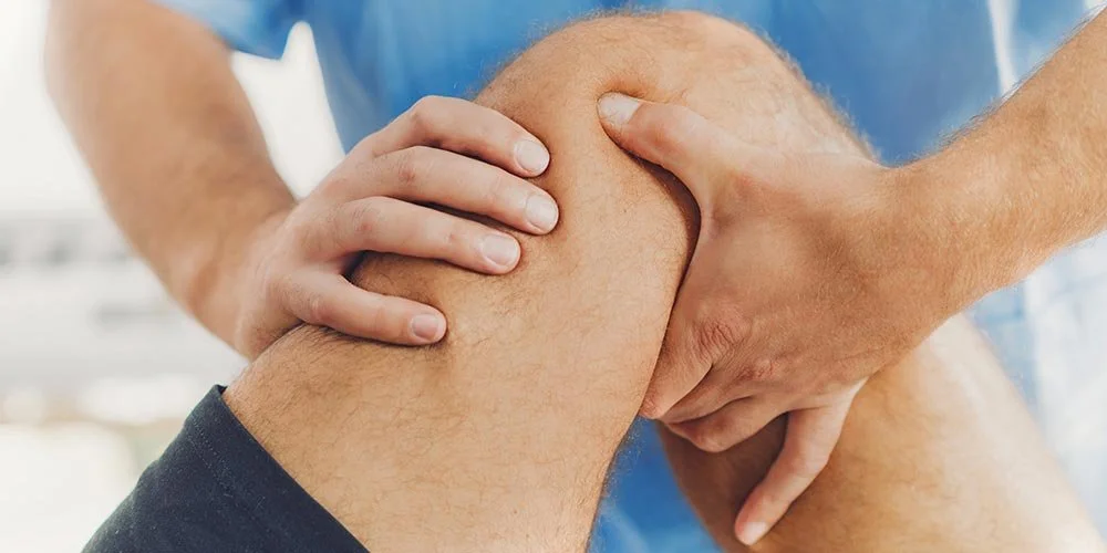 Person sitting with knee pain during movement, showing signs that may indicate an ACL injury.