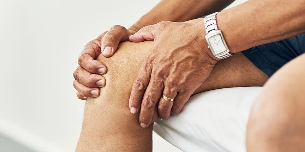 Person holding inner knee area, showing pain associated with an MCL tear and medial knee ligament injury