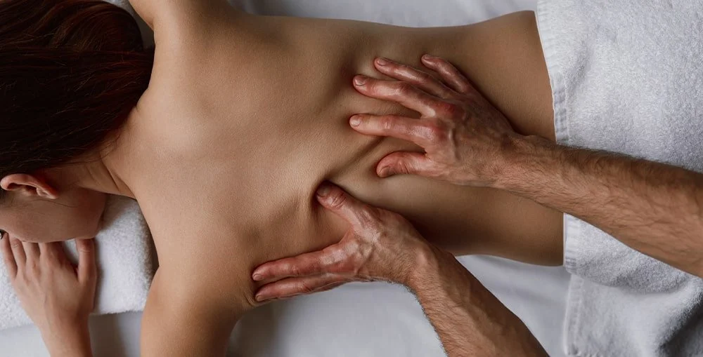 Massage therapist using gentle pressure to promote relaxation and stress relief during treatment at West End Wellness