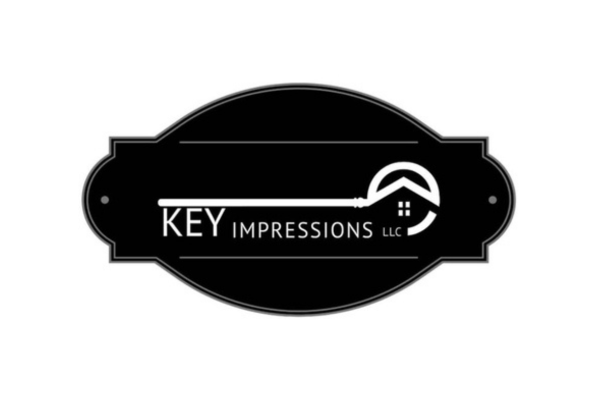 Logo for Key Impressions LLC featuring a black oval background, a key shape with a house outline incorporated, and the company name.