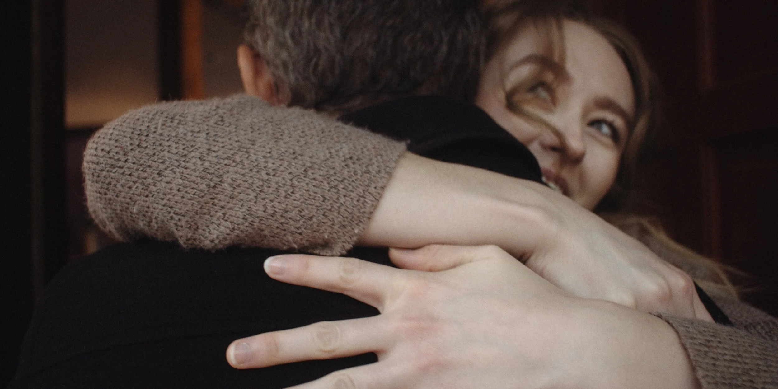 Close-up of two people embracing, one person smiling.
