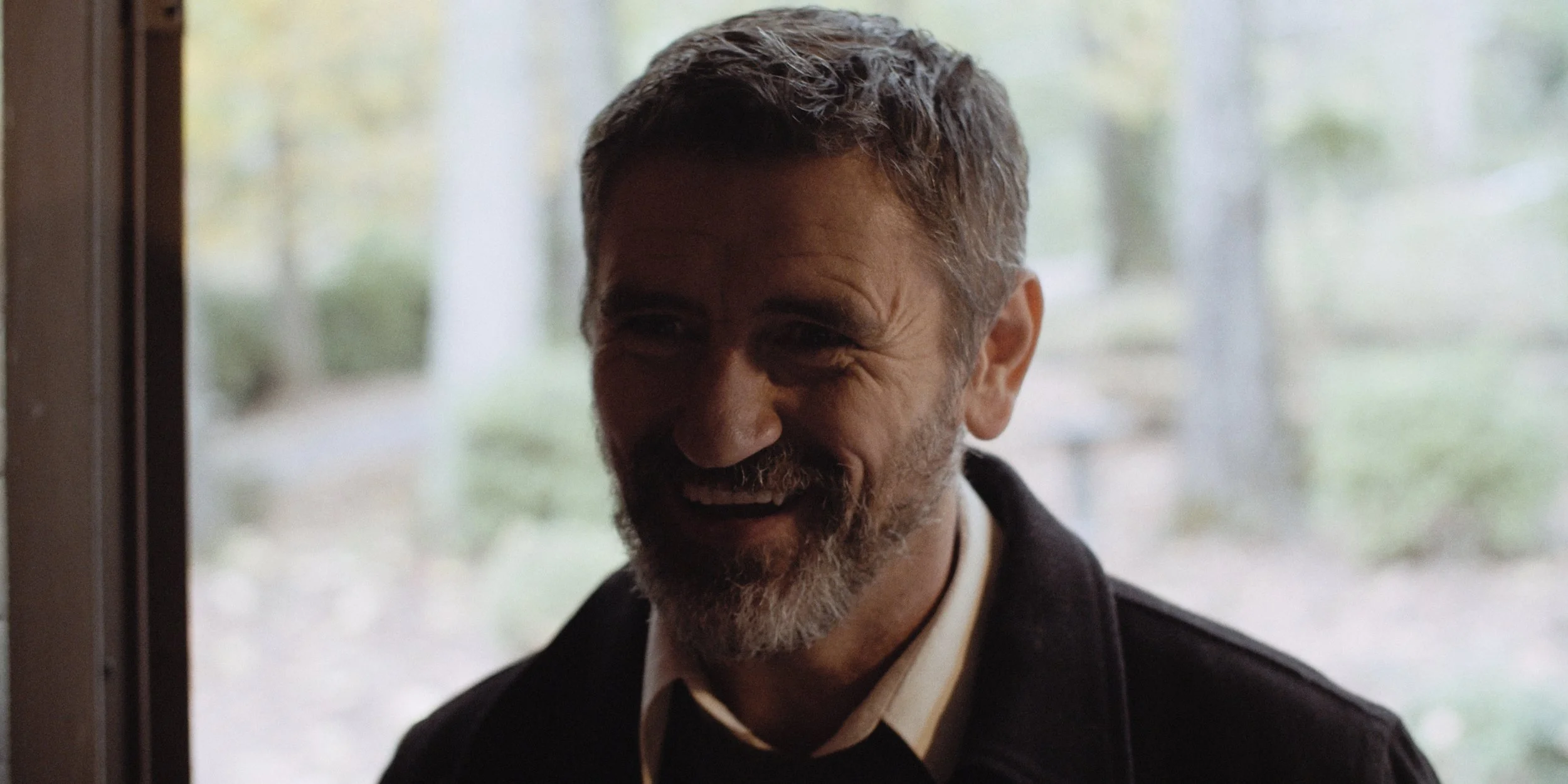 Smiling man with a beard standing in a doorway.