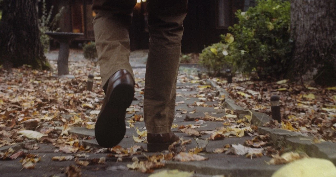Person walking on a leaf-covered path in autumn.