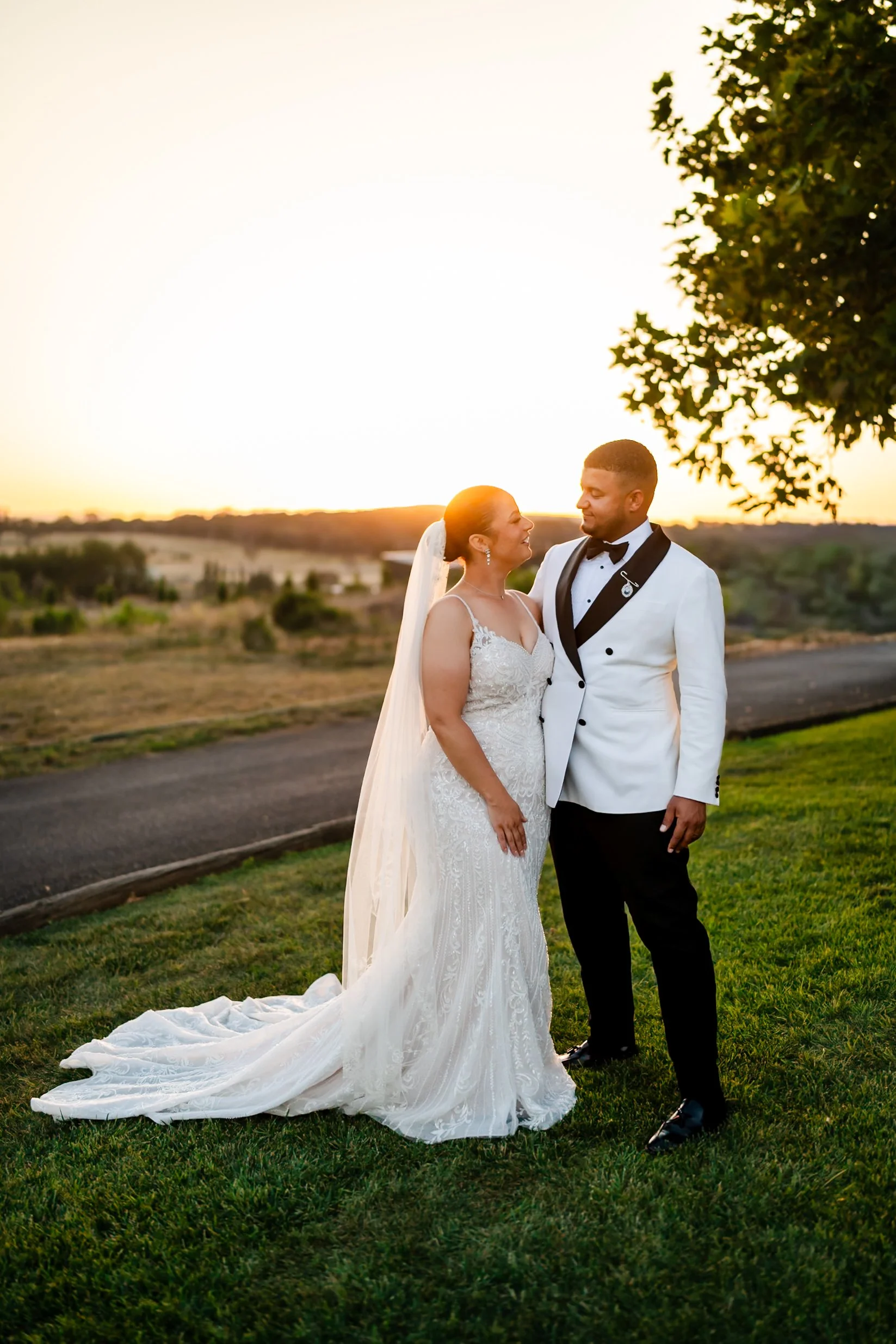 Bride and groom stand together on the lawn at sunset overlooking the vines at Shaw Estate, Murrumbateman