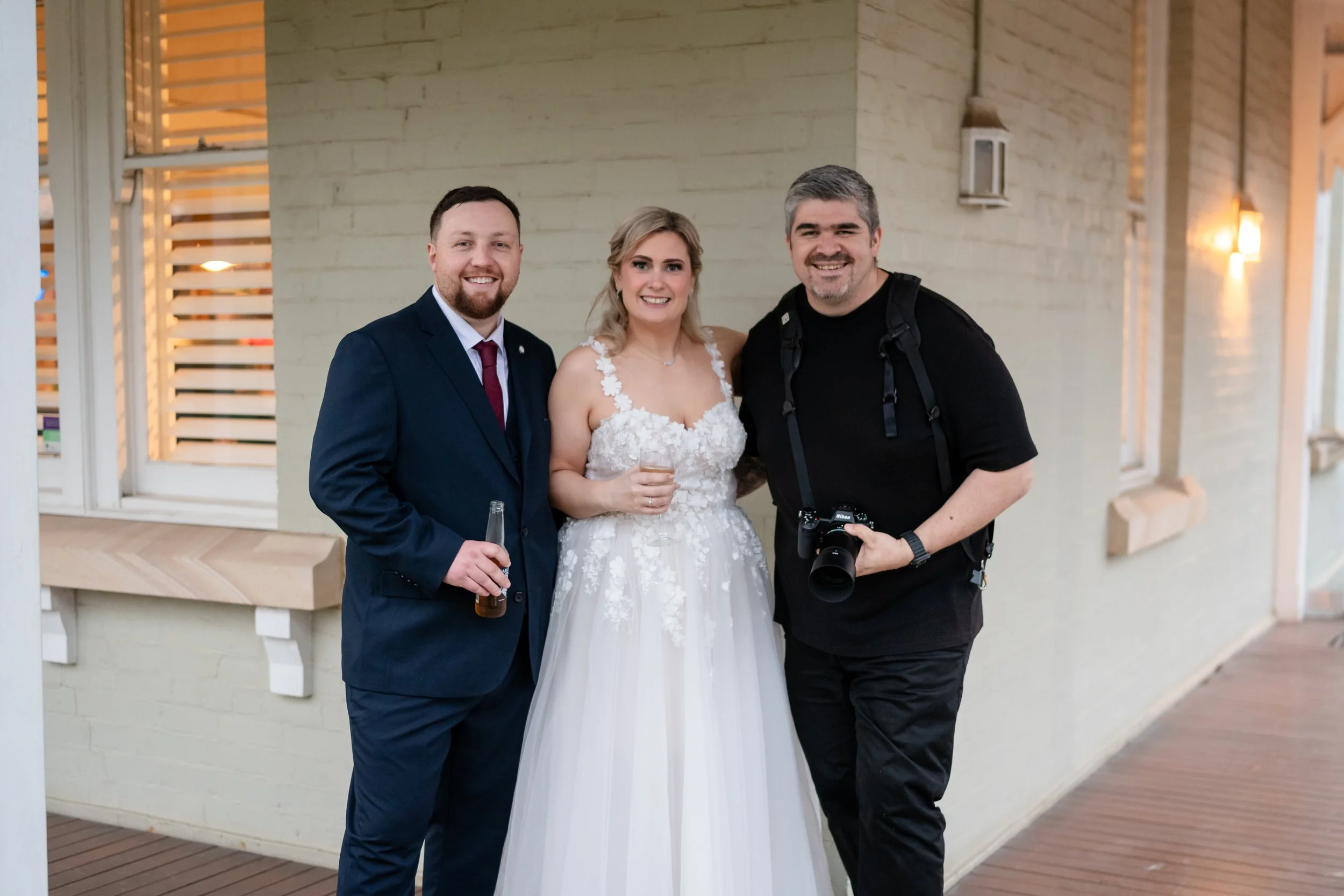 Jack Ham with a bride and groom on the verandah at Settlers, Mulgoa, camera in hand