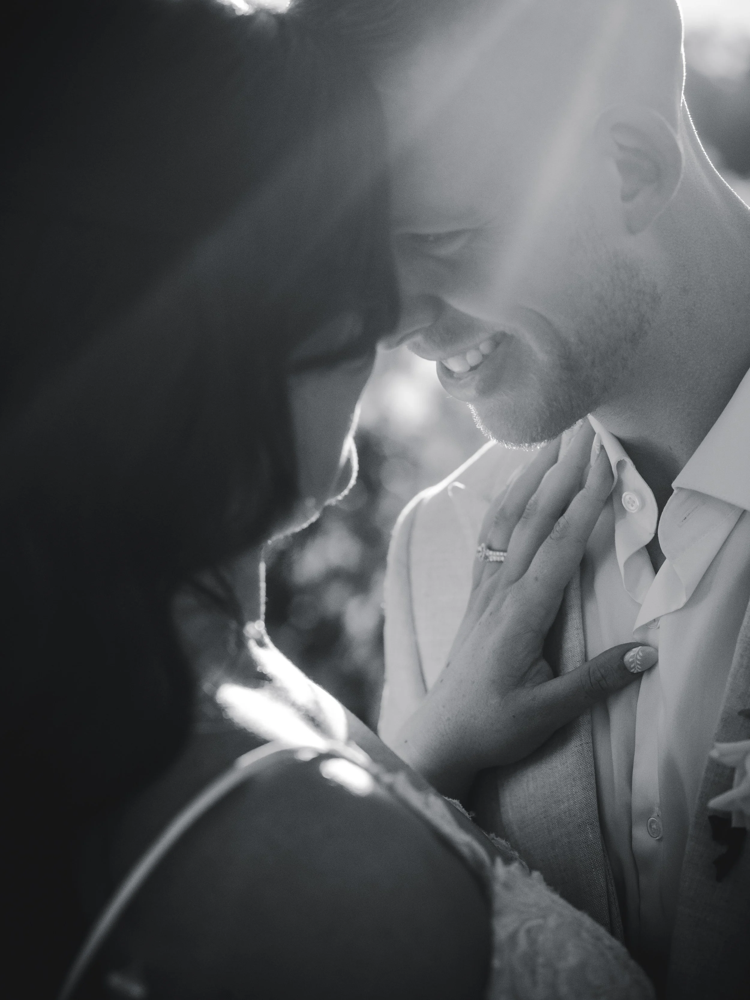 Groom holds his bride close, her hand on his chest, in soft light at Château Élan in the Hunter Valley