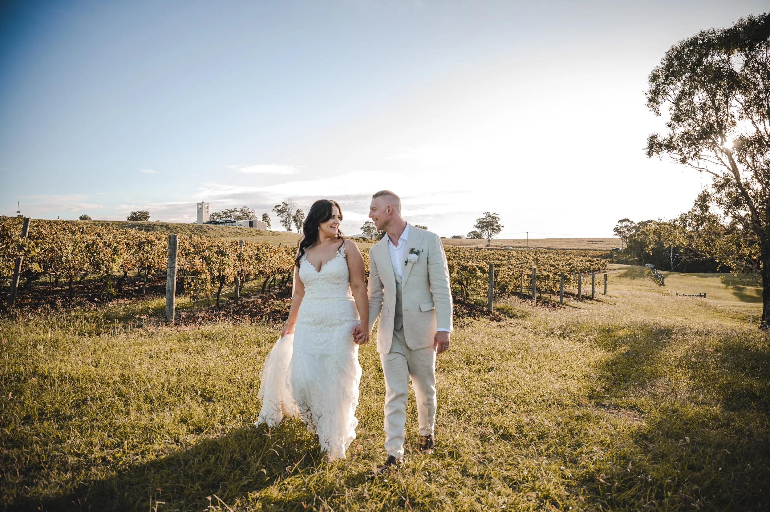 Bride and groom walk hand in hand through the vineyard rows at Château Élan, Hunter Valley