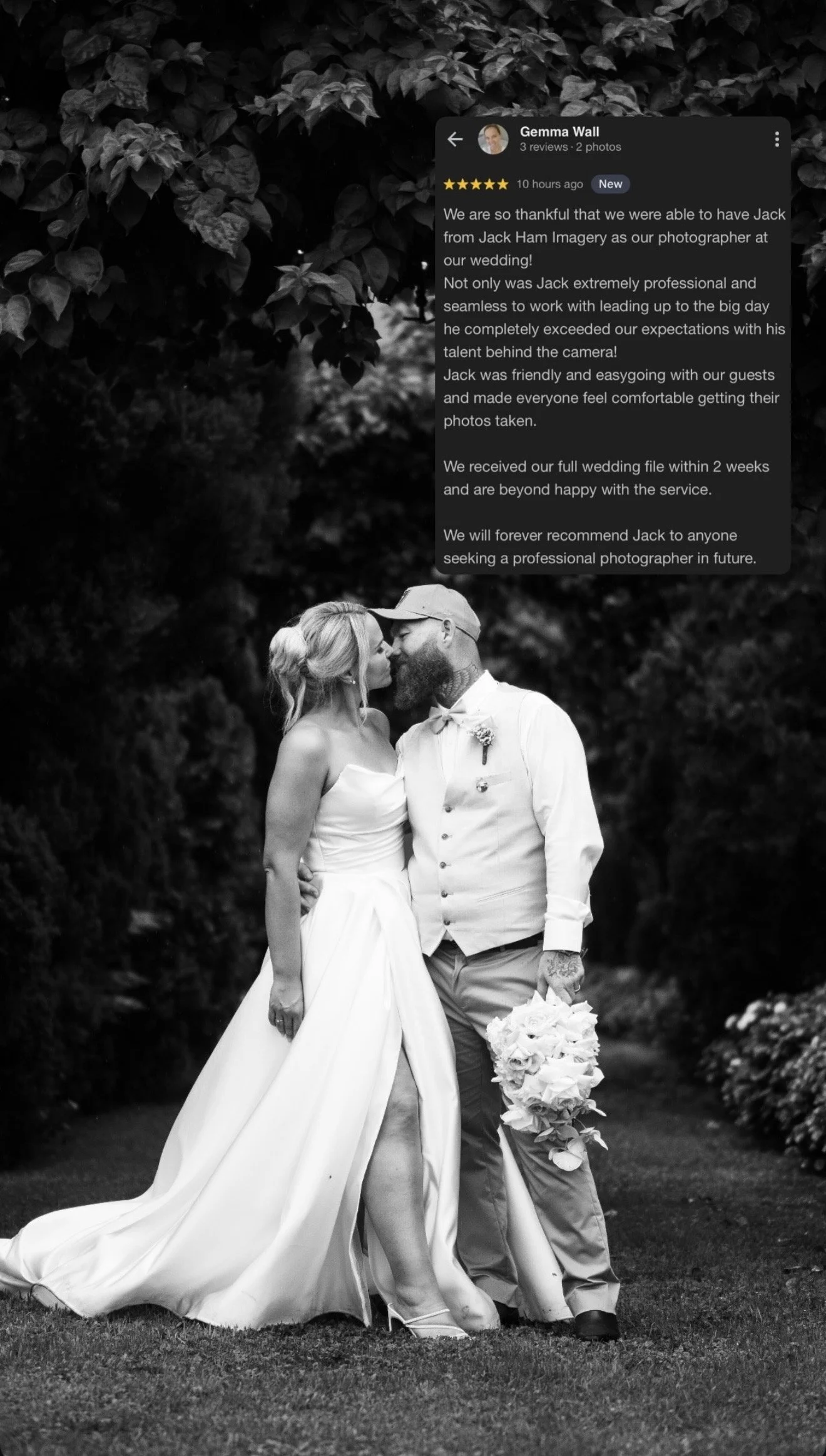 Black and white photo of a bride and groom in wedding attire, kissing outdoors, with trees in the background.