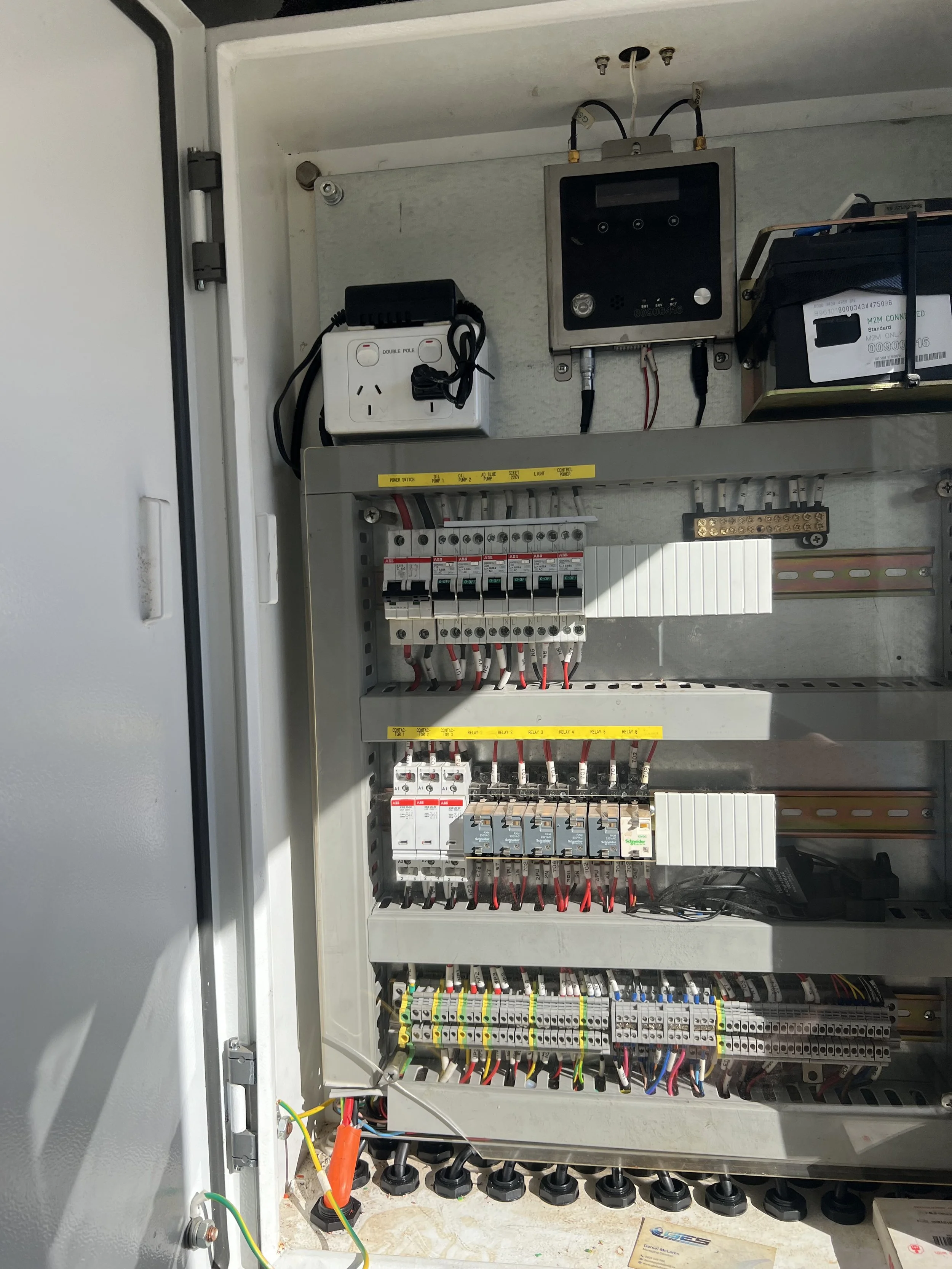 An electrical control panel with various circuit breakers, wiring, and devices inside an open metal enclosure. Relays for commercial use