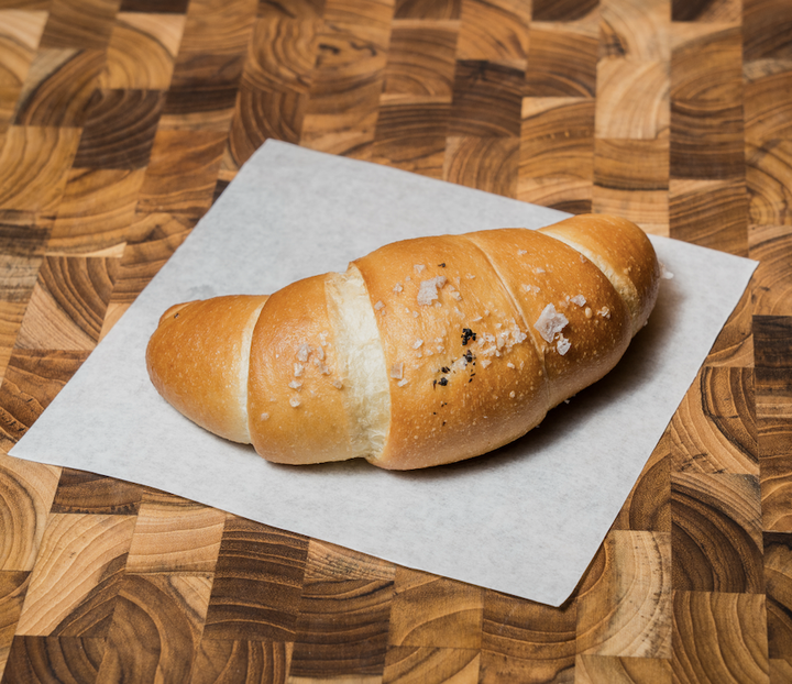 A butter roll on a piece of white paper on a wooden surface