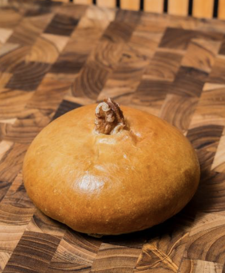 A red bean bread with a walnut in the center, placed on a wooden surface.