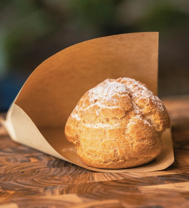Cream puff pastry on a wooden table with parchment paper wrapping.