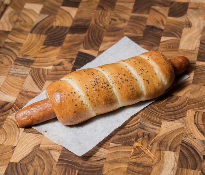 Baked bread with sausage inside on a wooden table