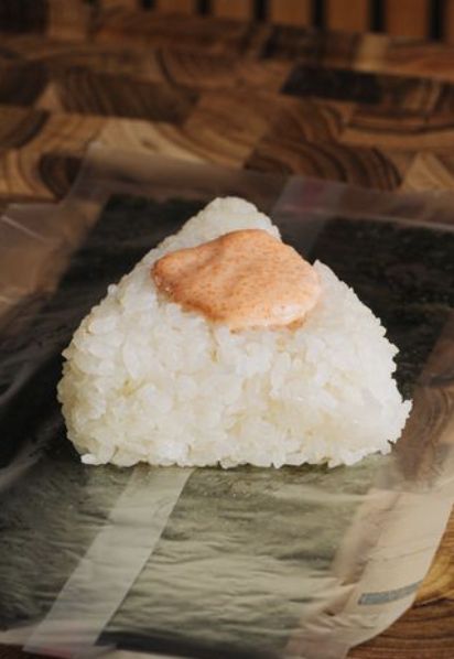 A onigiri rice ball with a mental mayo on top, placed on a seaweed wrapping.