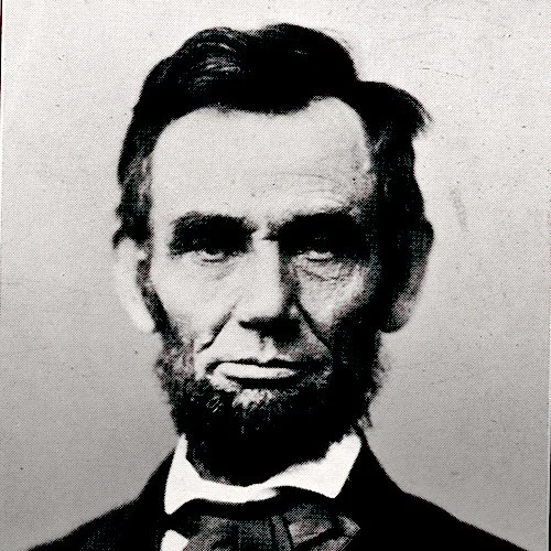 Black and white historic photograph of Abraham Lincoln with a serious expression, wearing a bow tie and suit.