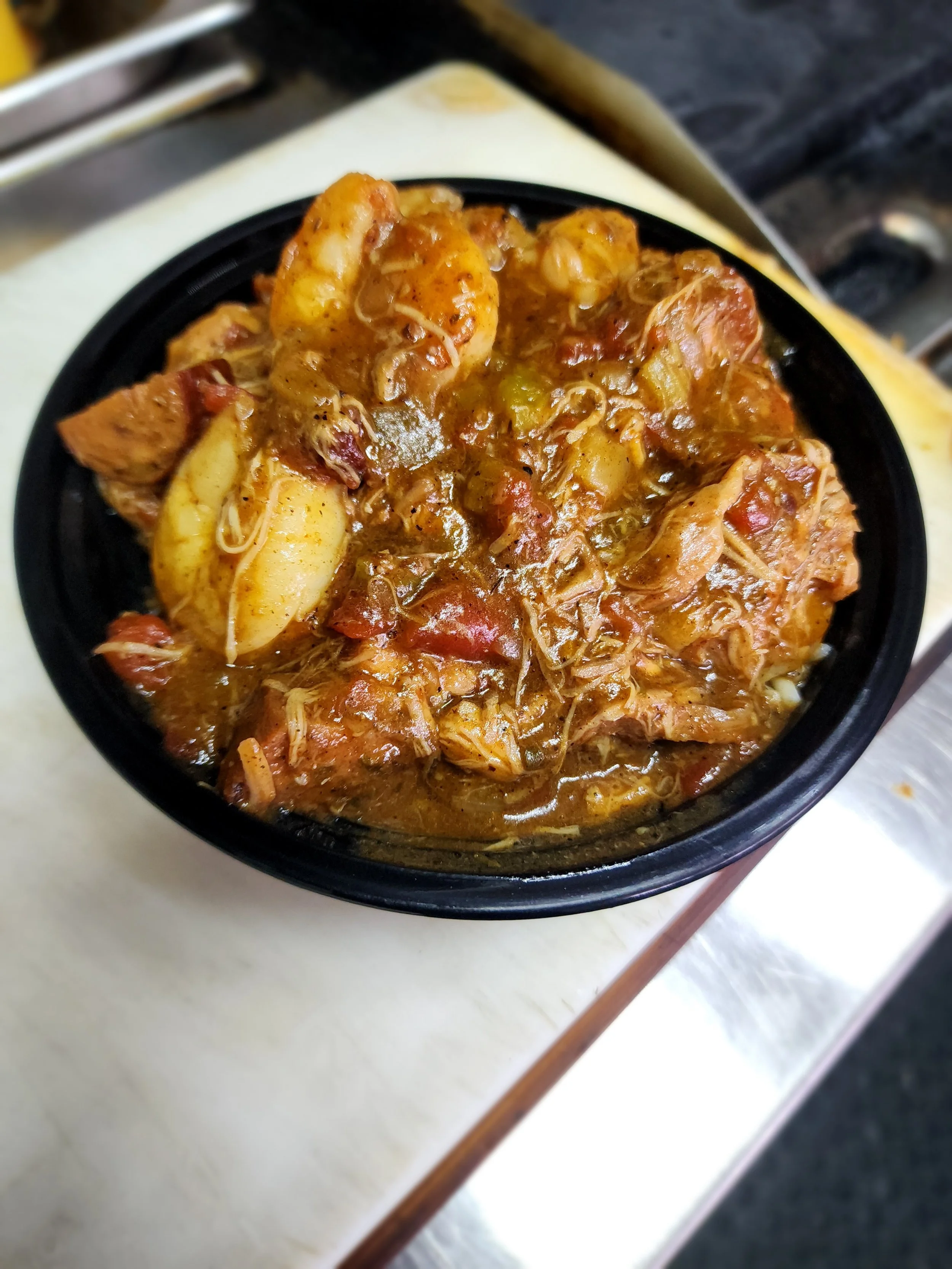 Plate of grilled lamb chops with a side of yellow rice and broccoli, garnished with a dark sauce.