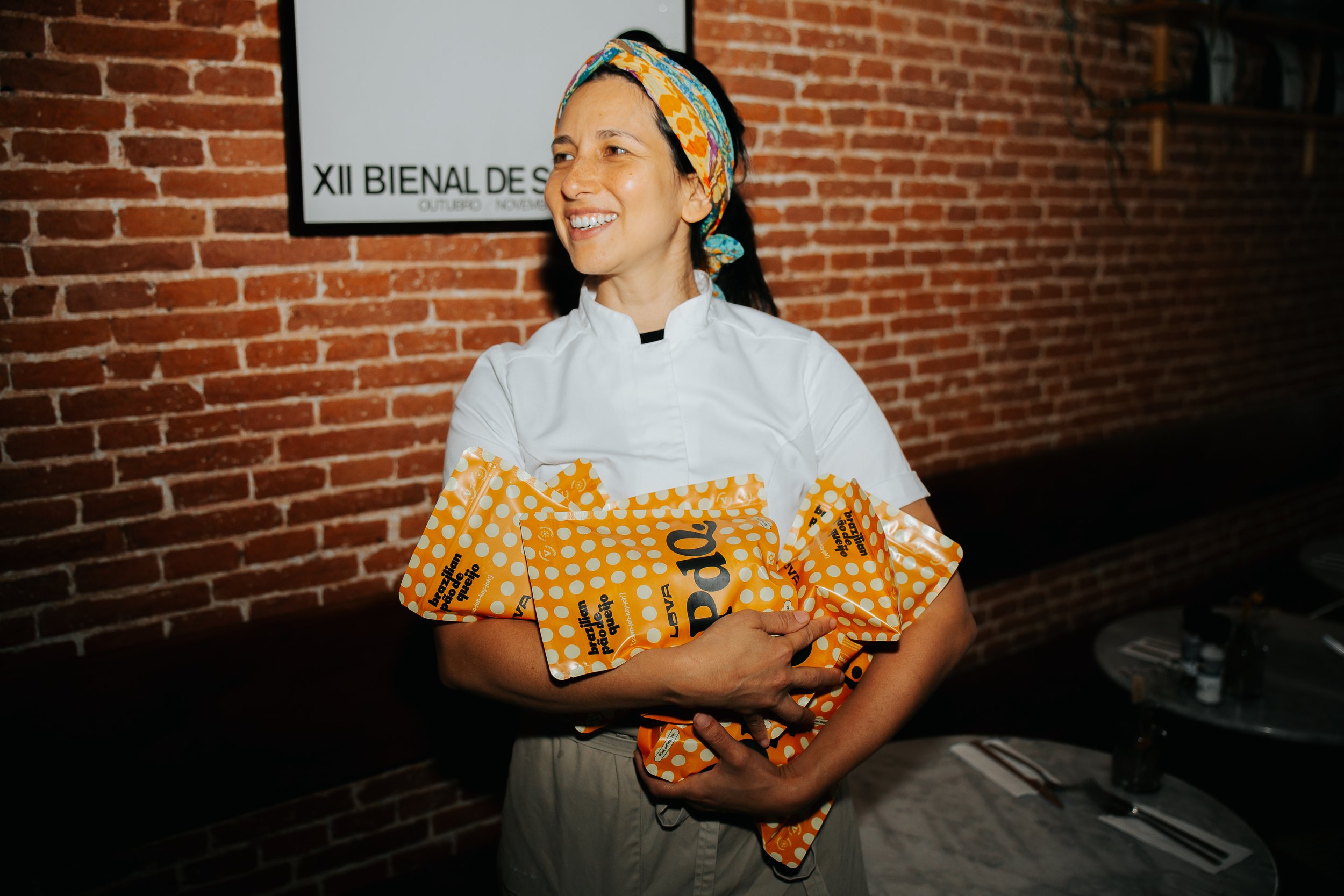 Nathalia, chef-founder of Lova, standing and holding many packs of PdQ, Lova's frozen, bake at home pão de queijo.