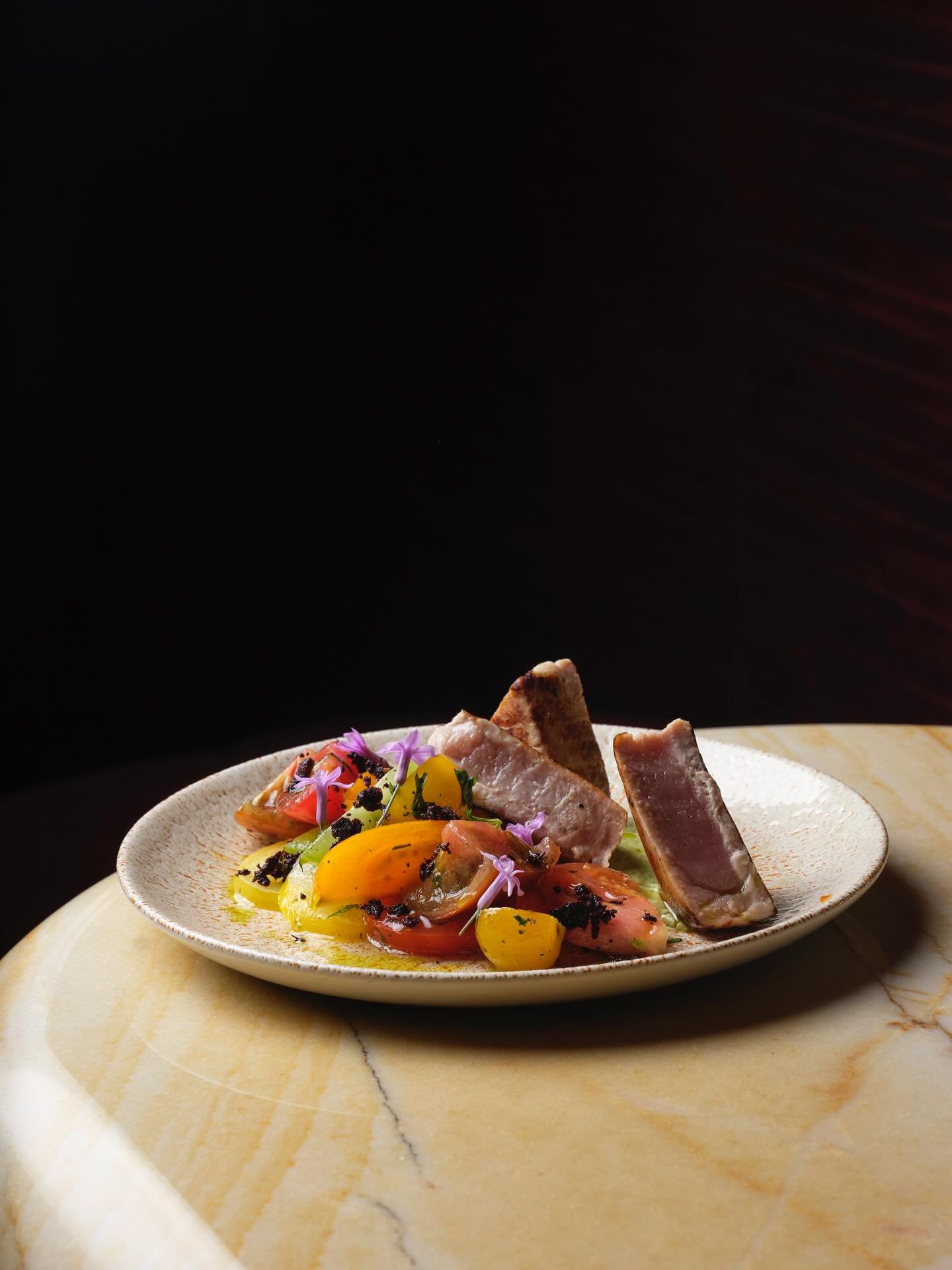 The perfect tuna steak is seared on the outside and deliciously rare on the inside served with a heritage tomato salad, smashed avocado, lemon &amp; olive dust.