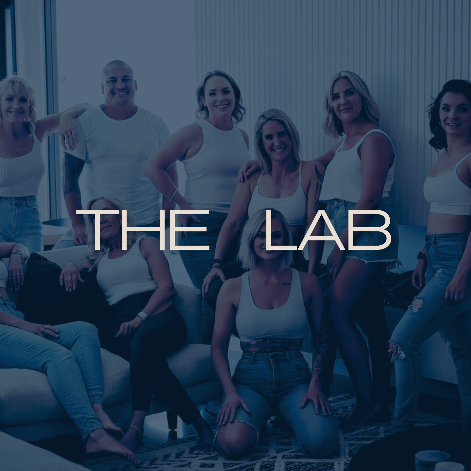 A group of women and one man in casual white clothing gathering in a modern lounge, with the text 'THE LAB' overlaid.
