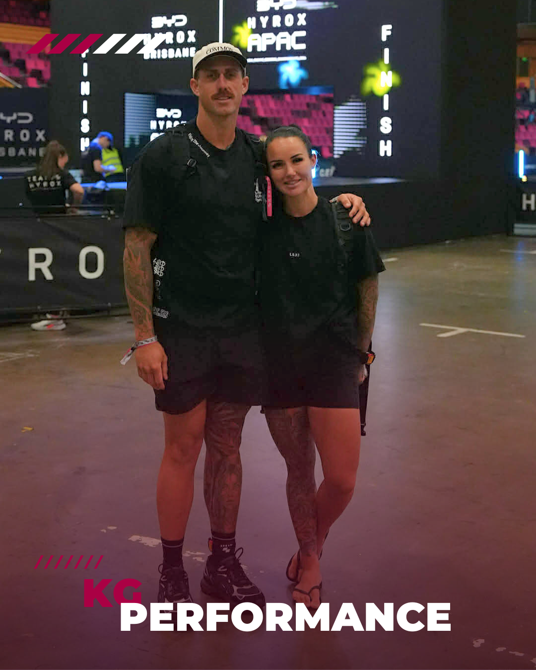 Two people, a man and a woman, standing together at an indoor event with a large screen in the background. The man is wearing a black t-shirt and shorts, a cap, and sneakers. The woman is wearing a black t-shirt and skirt, with tattoos on her legs, and sandals. The background displays the words 'Hyrox APAC' and 'Finish.' The image has the text 'KG PERFORMANCE' at the bottom.
