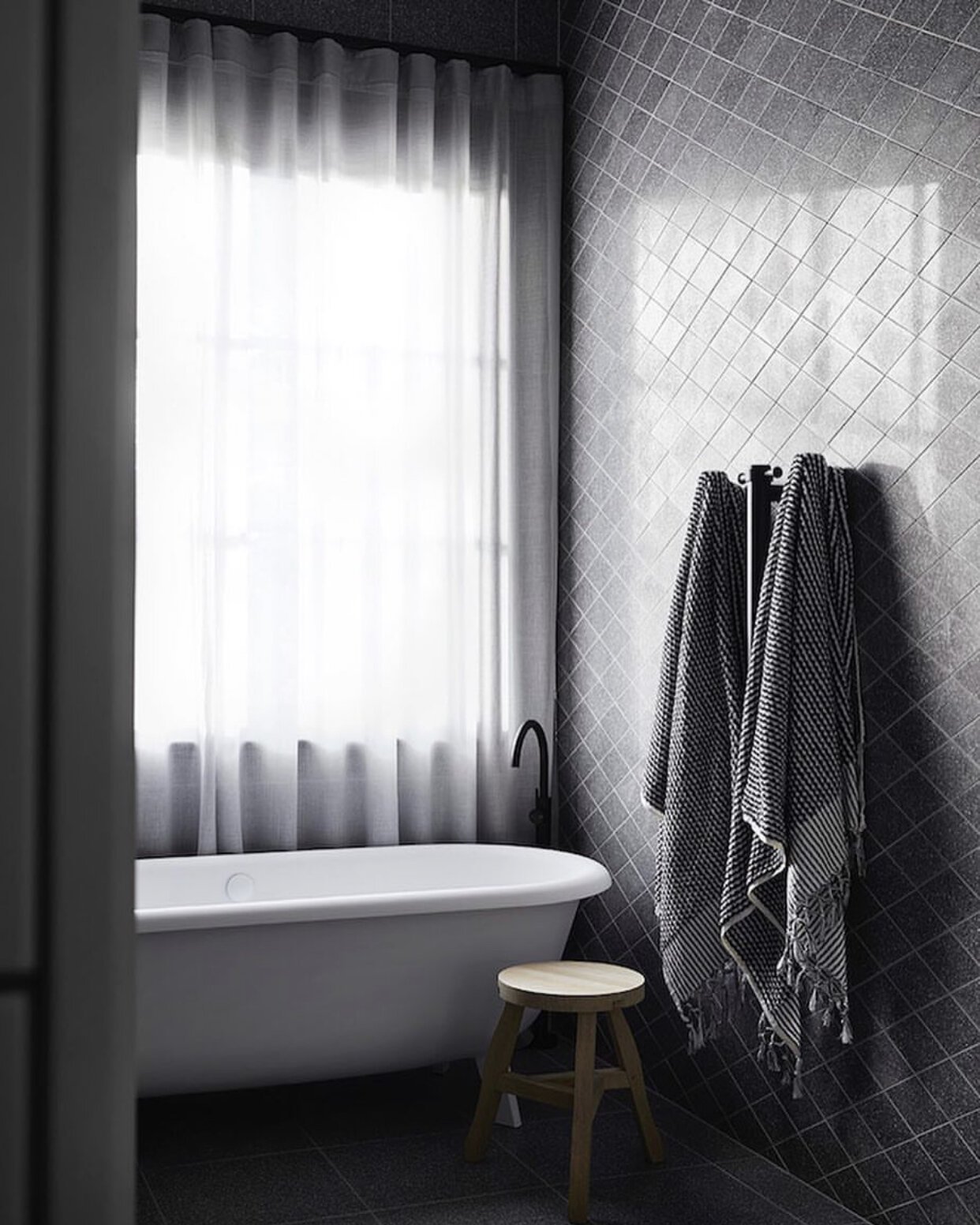 Black tiles placed diagonally on the bathroom wall create a diamond-shaped pattern