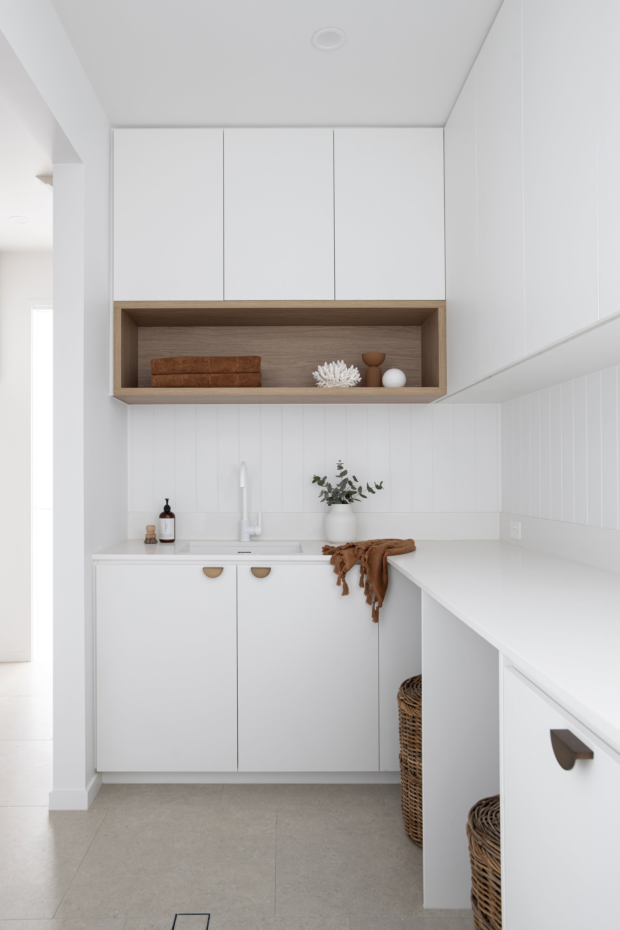 White wooden cabinets for laundry room storage with laundry shelves on top in coral house laundry design plans for laundry renovation