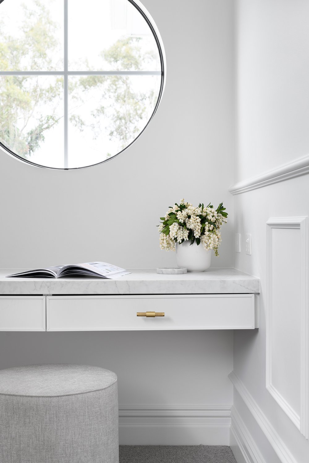 Hamptons study nook design with built in desk with marble top and round wheel window