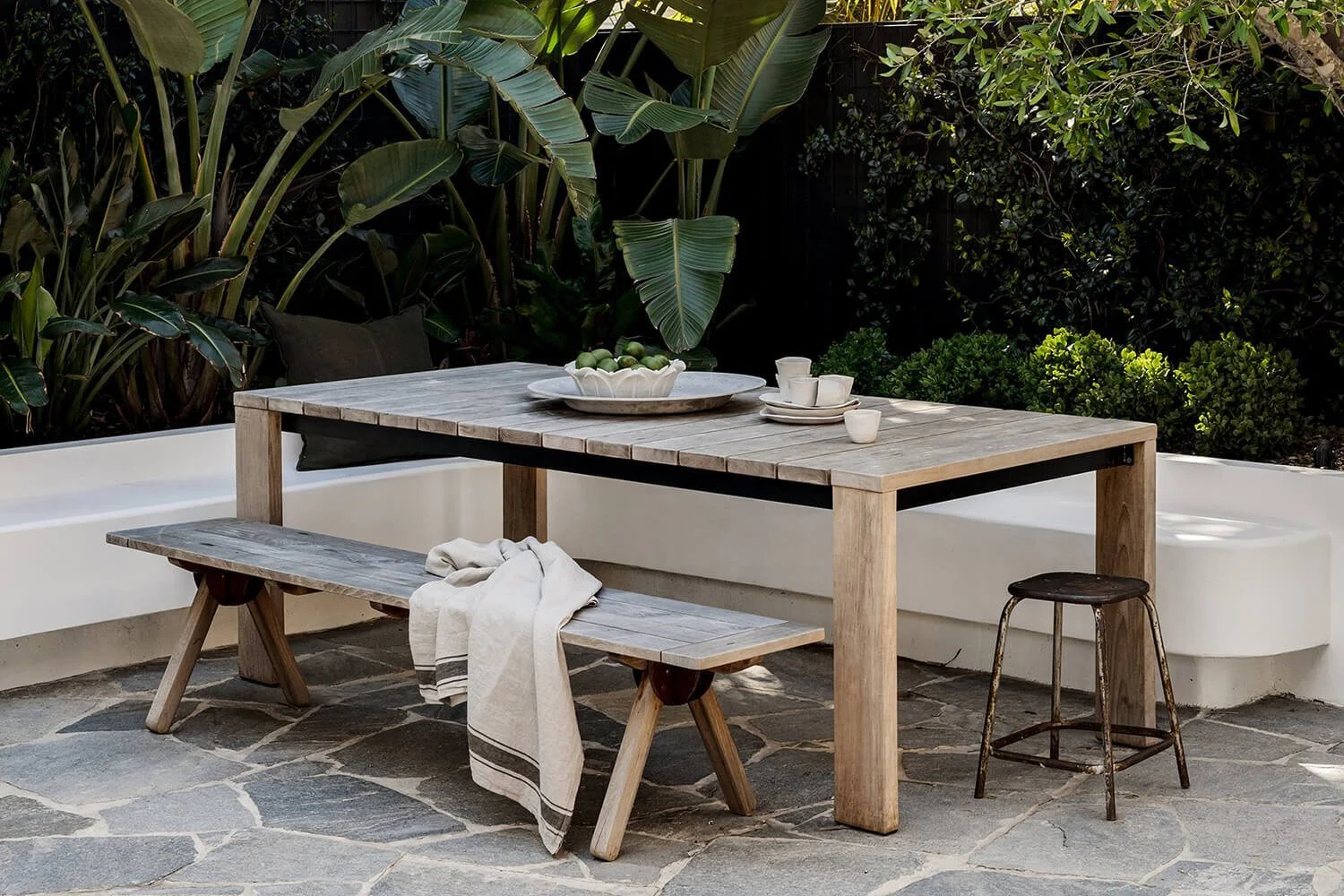 Outdoor living area with wooden table and benches with stone flooring