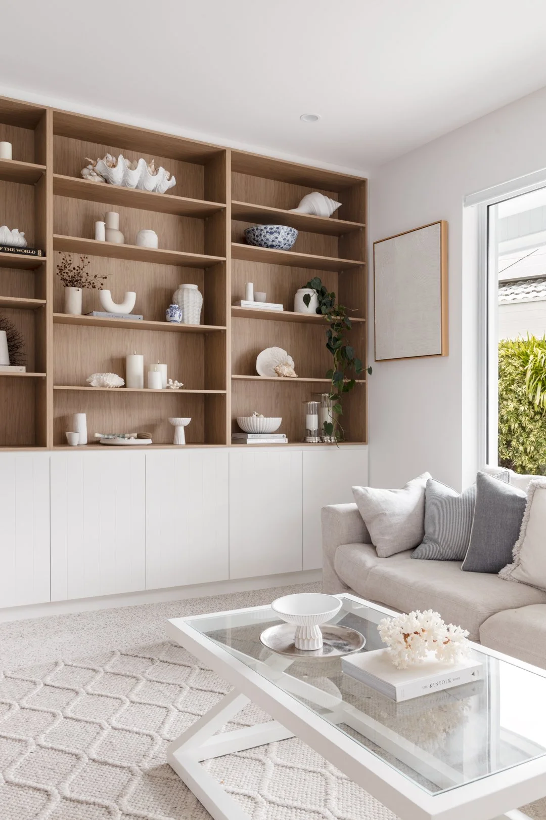 Built-in oak bookshelves above white cabinetry in a light-filled living room