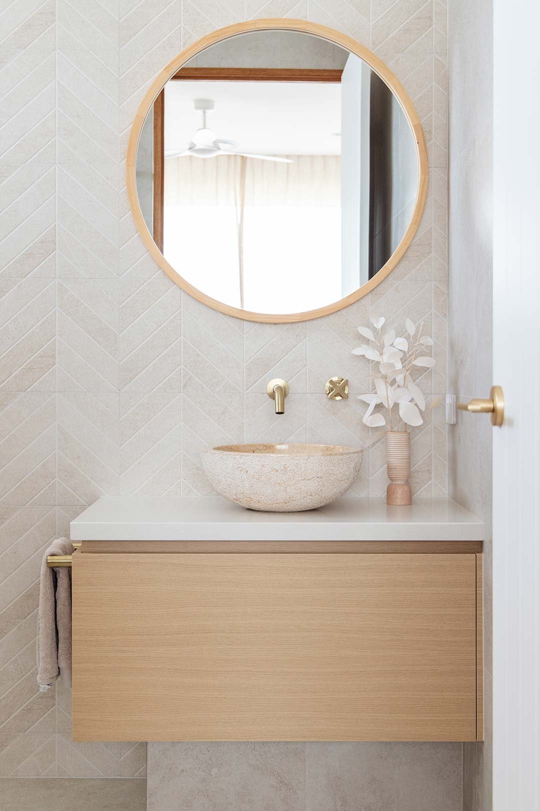 A warm neutral bathroom with a chevron tile pattern