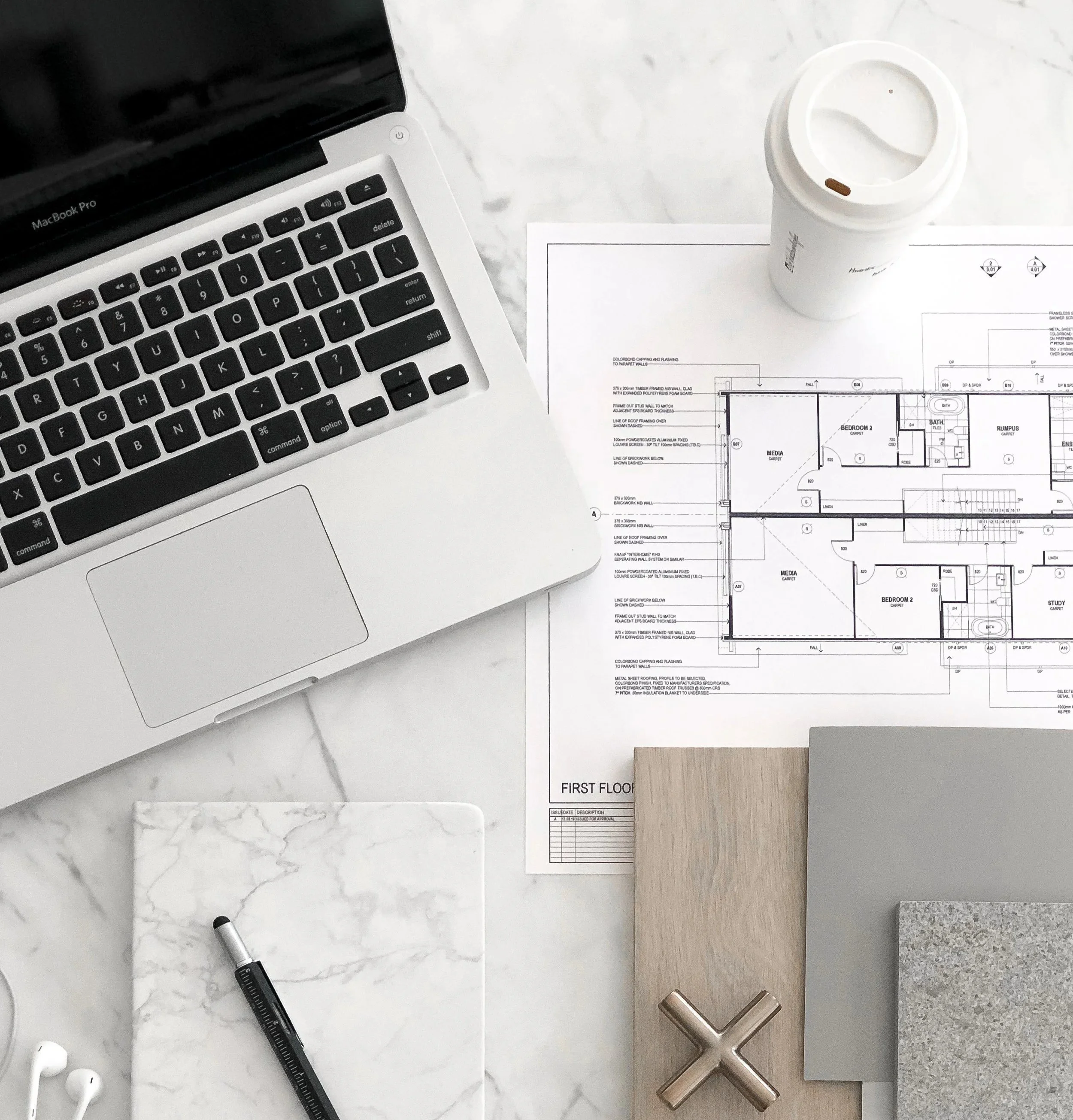 Floor plan on a desk with material samples, laptop and notebook, ready for review