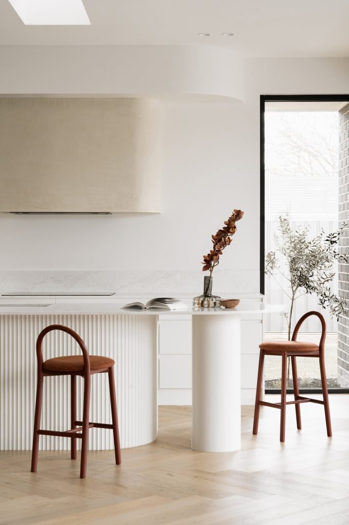 Curved kitchen island dining table with two stools seated at the rounded end facing each other
