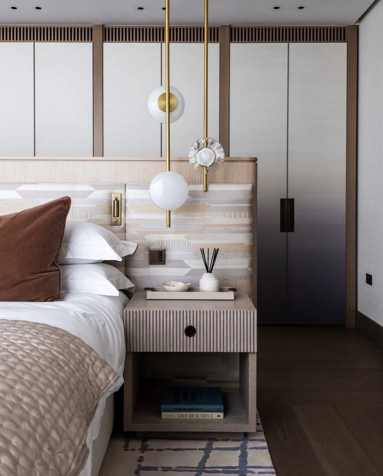 Neutral master bedroom with pendant lights hung above bedside tables, freeing up bedside table space — smart lighting placement at the floor plan stage.