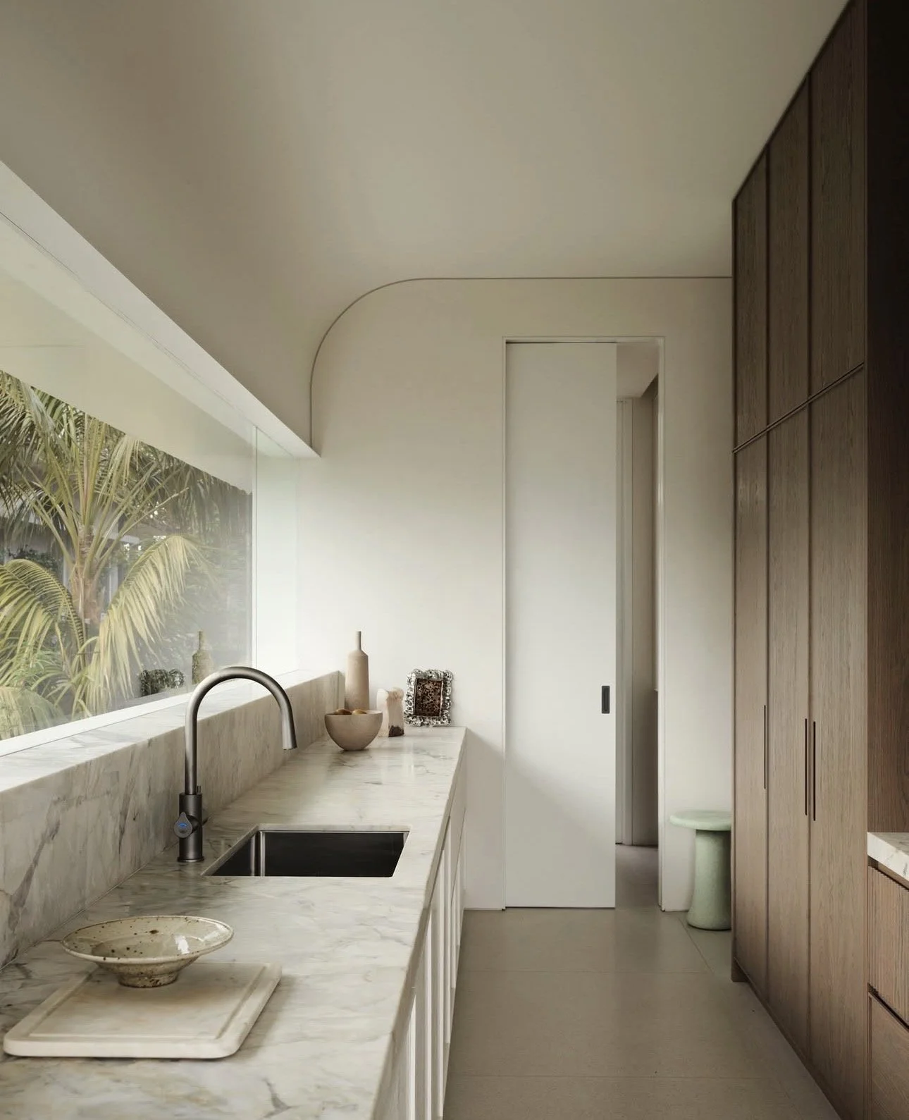 Galley-style kitchen with window splashback above the benchtop bringing in natural light and garden outlook.