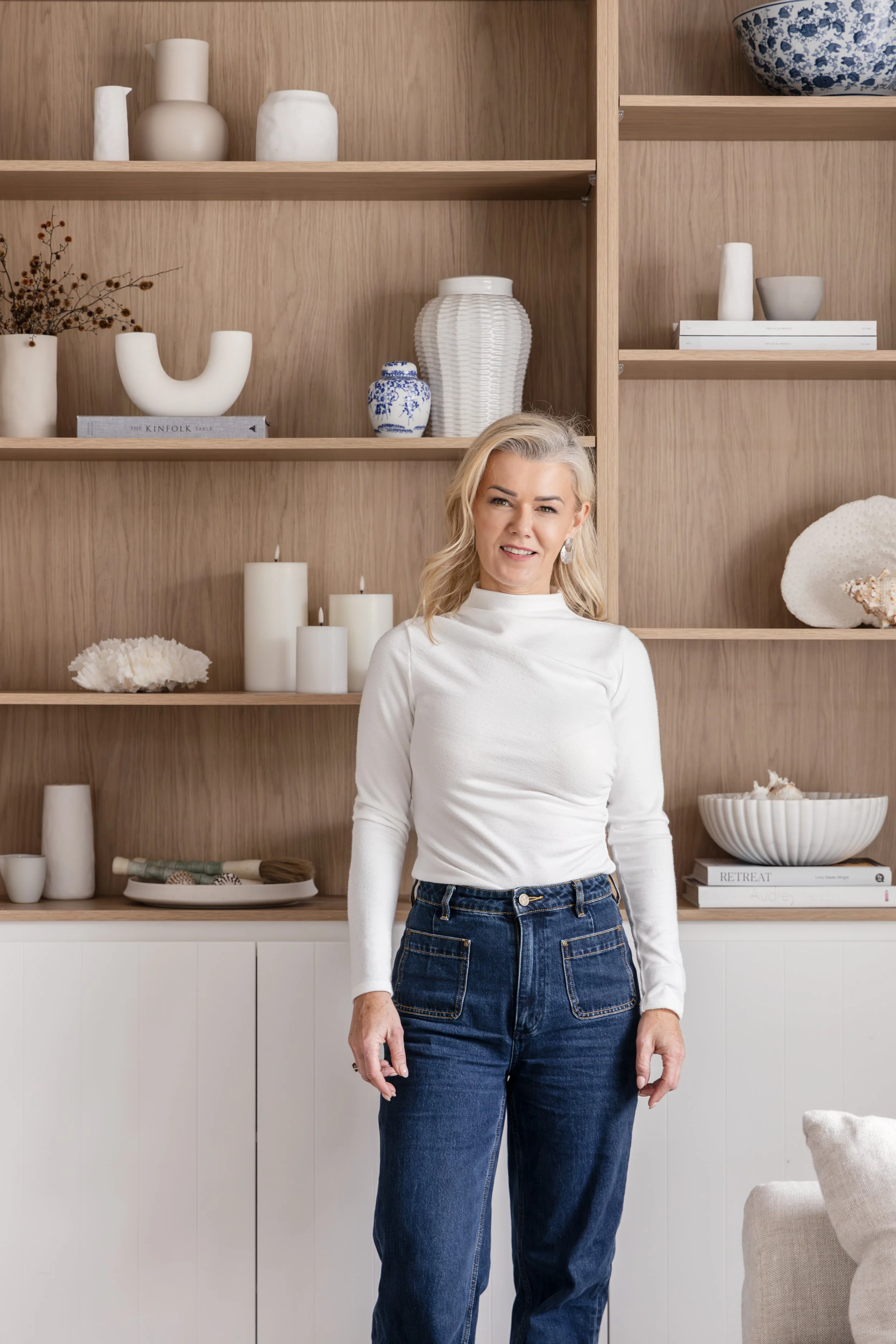 Ania Mikina, Home Design Strategist and co-founder of Zephyr and Stone, standing in front of a styled timber shelving display