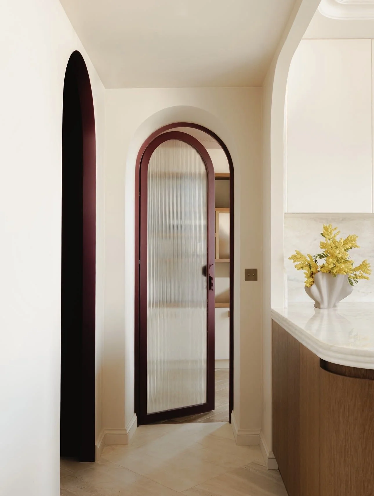 Curved arched glass door leading to a pantry, turning a functional doorway into a design feature.