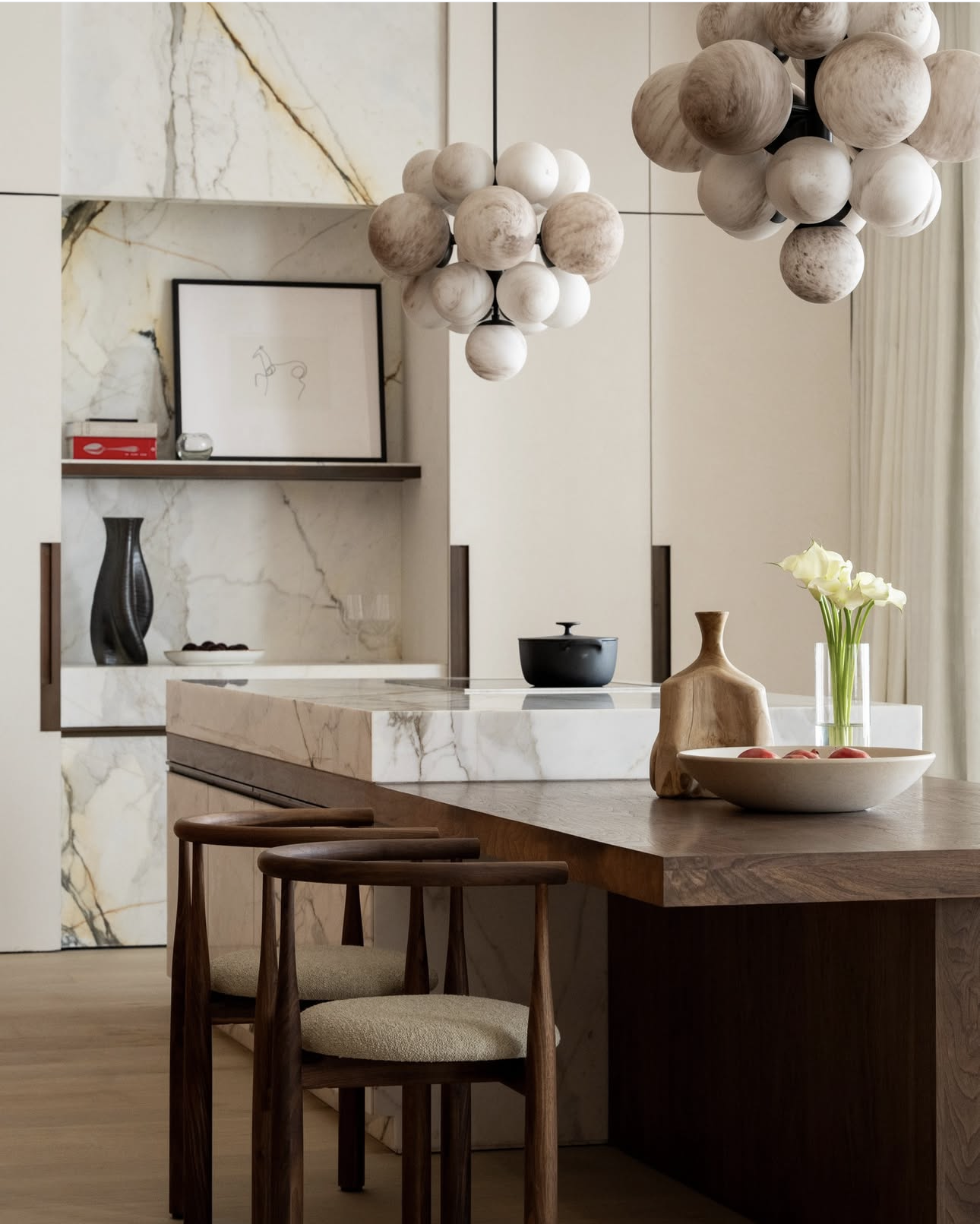 Timber dining table at dining height attached to a marble kitchen island bench, with timber dining chairs