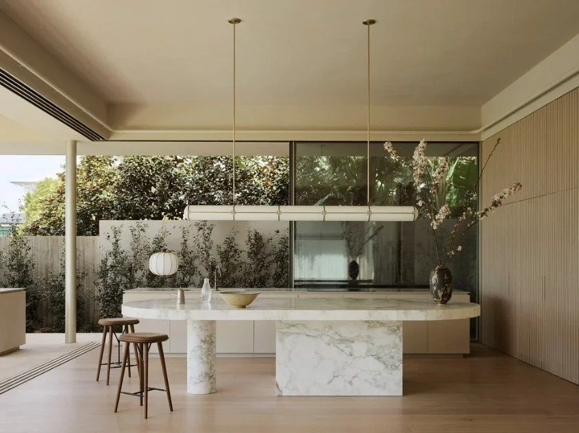 Oval marble kitchen island bench with two timber stools at the rounded end
