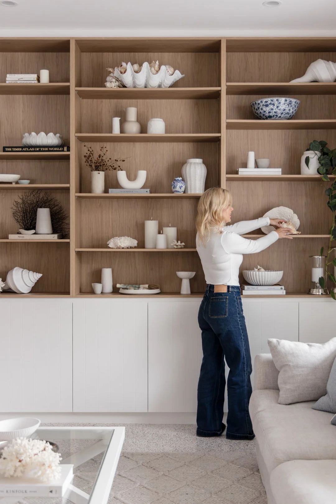 Built-in bookshelves in a living room, with timber shelving above white panelled cupboards.