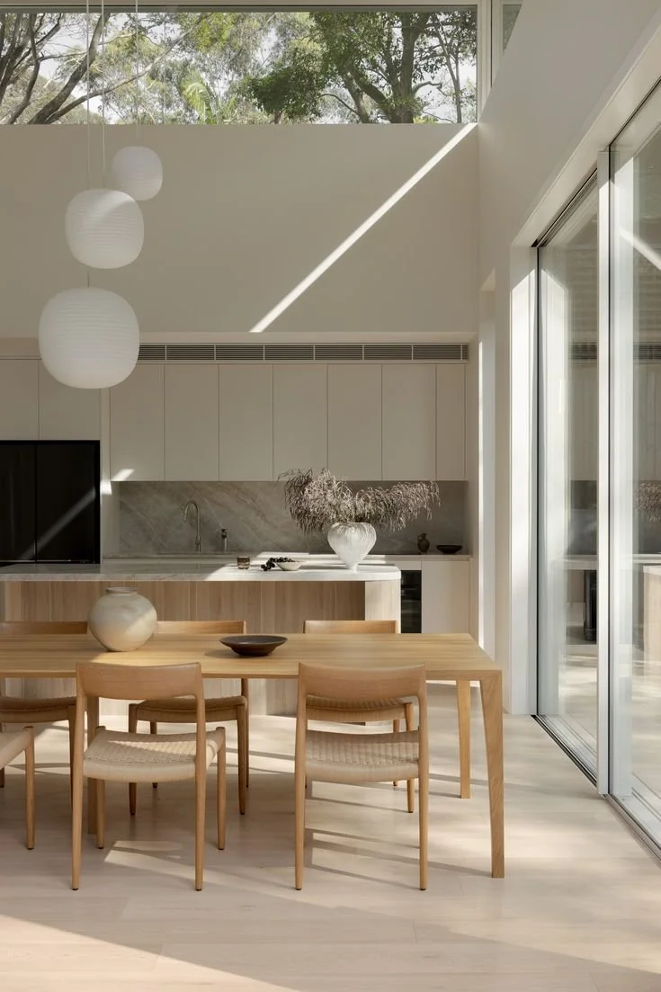 Open plan kitchen and dining area with a timber dining table positioned beside the island bench