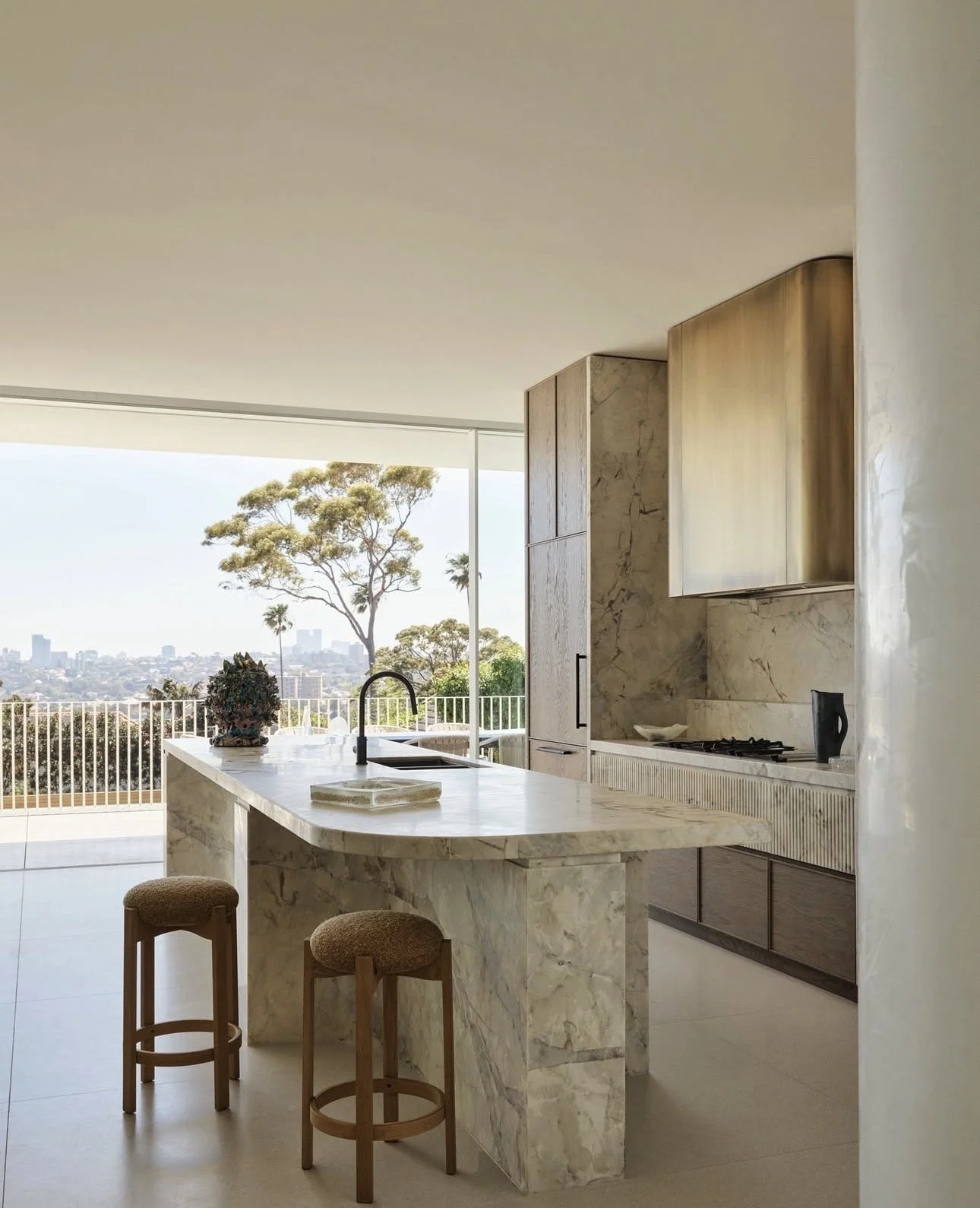 Light-filled kitchen with island bench seating positioned to capture garden views through full-height windows.