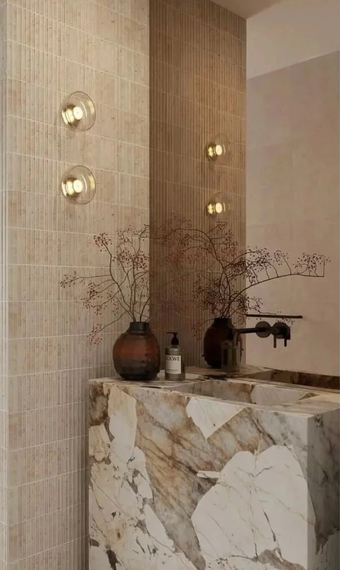 Sculptural marble basin with glass wall lights and wall-mounted black tapware