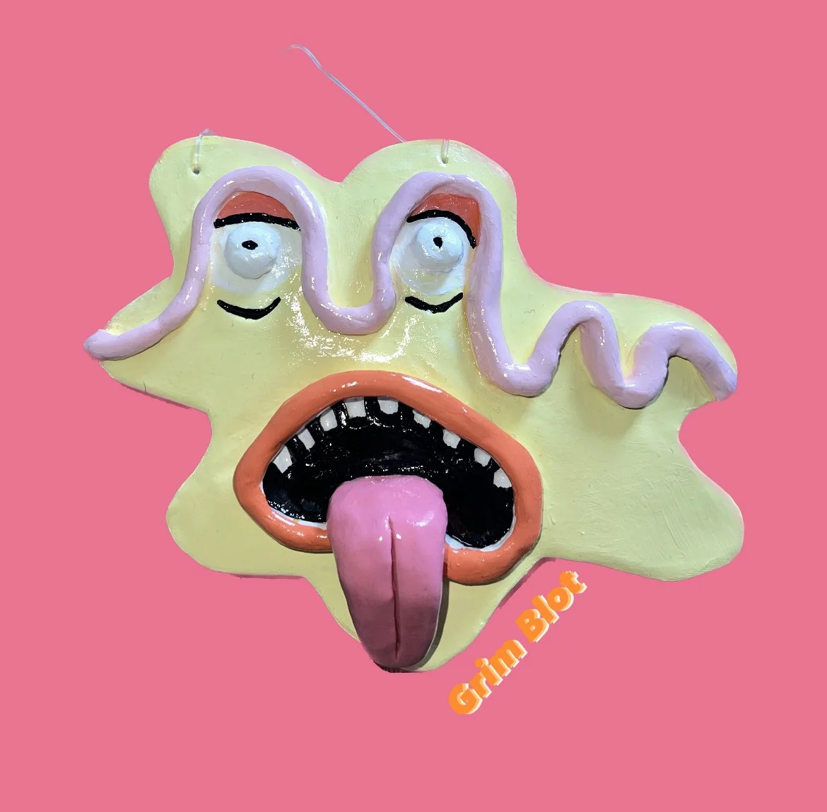 Colorful, surreal sculpture of a starfish with exaggerated facial features, including large eyes, painted lips with tongue sticking out, and a pink inside part of the tongue, set against a pink background, with orange text reading 'Grim Blog' in the