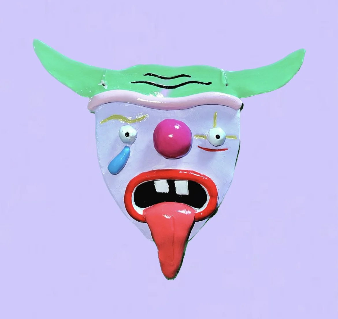 Colorful clown mask with green horns, pink nose, red tongue, and exaggerated facial features on a purple background.