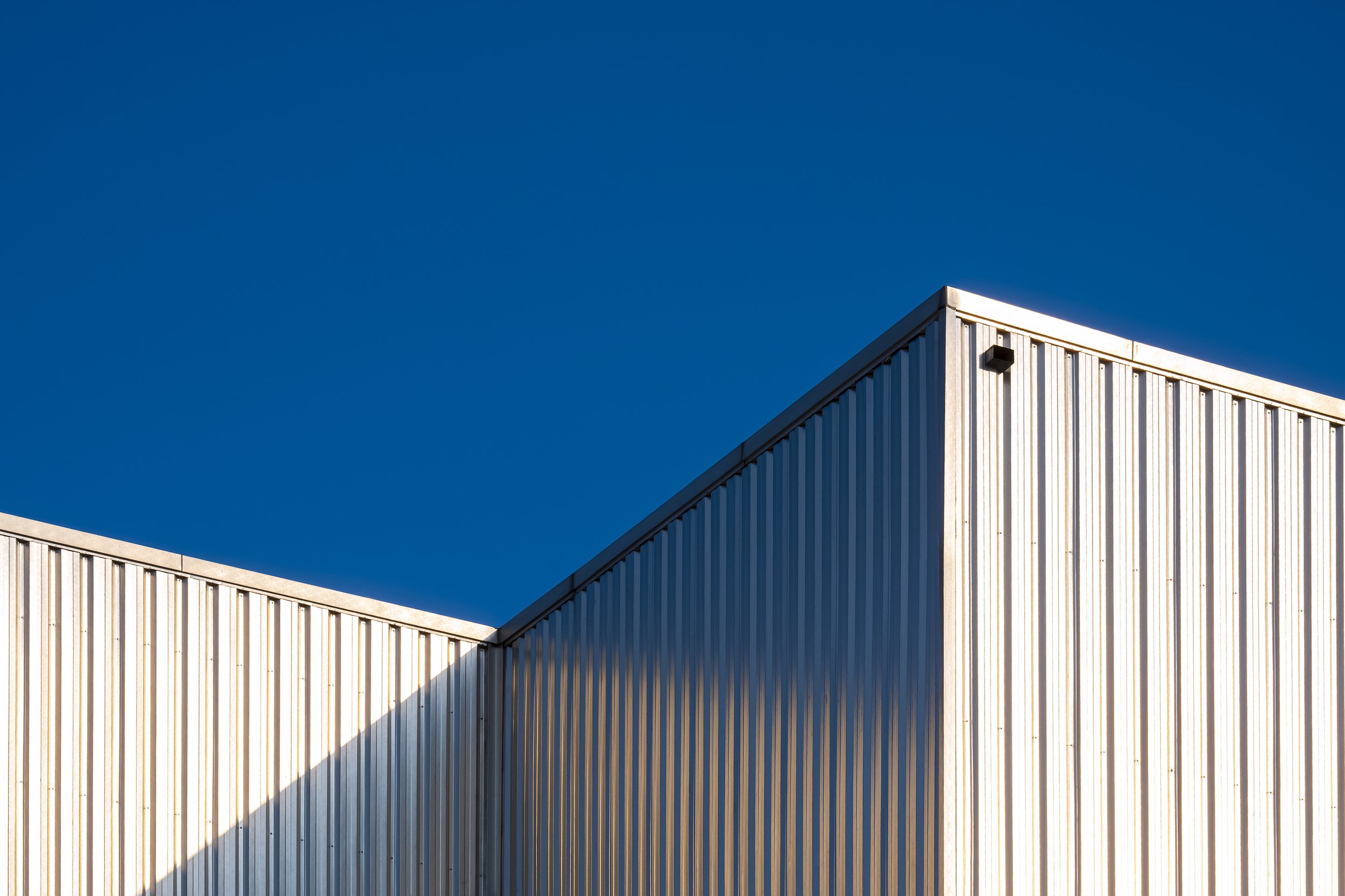 Close-up of a modern building with metallic siding under a clear blue sky.