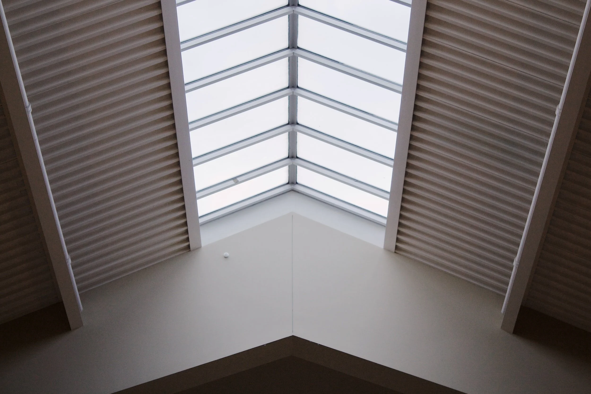 View of a skylight window in the ceiling, framed by beige-colored sided walls with ribbed panels.